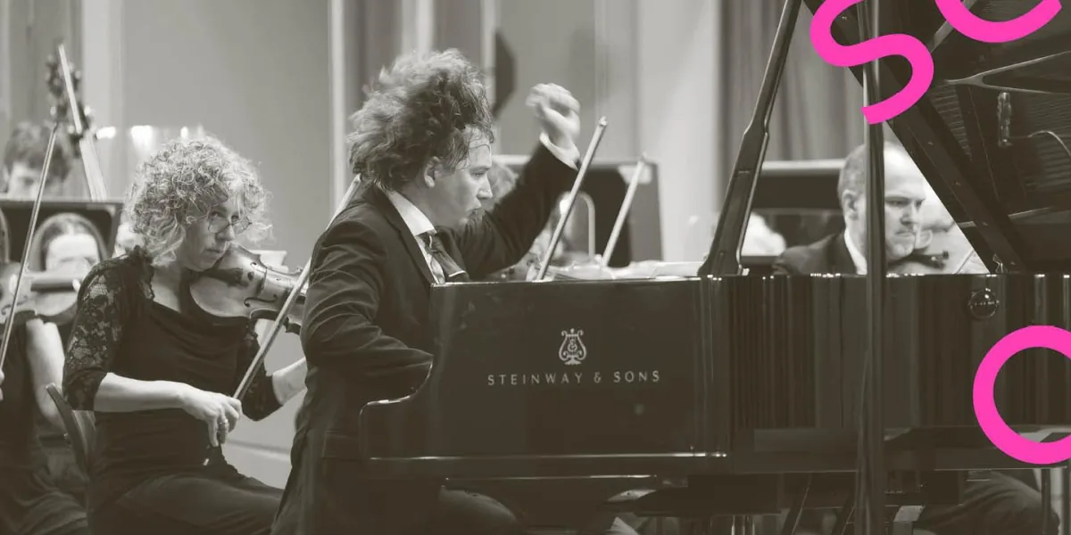 Maxim Emelyanychev plays piano while the orchestra performs behind